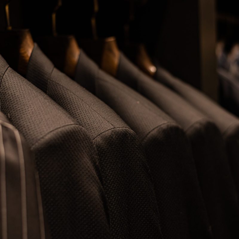 wardrobe with men's clothes in dark colors. jacket, down jacket, shirt. men's shirt earth tone color polite color for work or casual wear Orderly with wood hanger there are Separated by color make easy to pick up